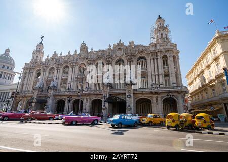 November 27, 2019, Havana, Cuba: Many vintage cars and the yellow Coco taxi on the road in front of Great Theater Stock Photo