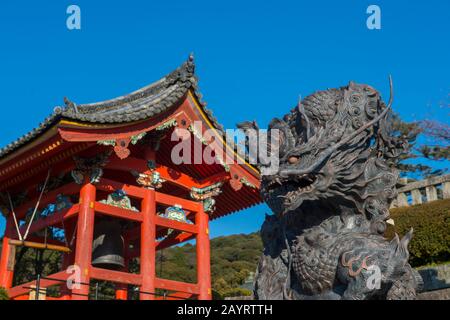 Close-up of a bronze dragon statue with the bell tower of the Kiyomizu-deraTemple (UNESCO World Heritage Site) in Kyoto, Japan, in background, which w Stock Photo