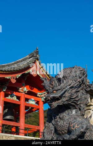 Close-up of a bronze dragon statue with the bell tower of the Kiyomizu-deraTemple (UNESCO World Heritage Site) in Kyoto, Japan, in background, which w Stock Photo