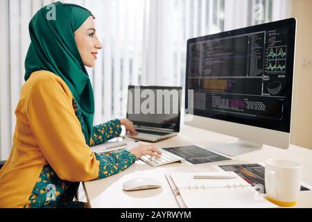 Female software developer impleDFHJDHGFJHSDFKHKJFHKDSJHFKJHDFKJDHting programming code she is working on laptop Stock Photo