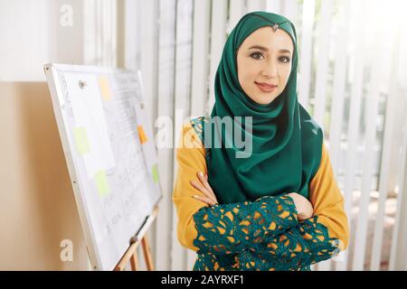 Portrait of young muslim businesswoman in traditional dress standing at whiteboard in office Stock Photo
