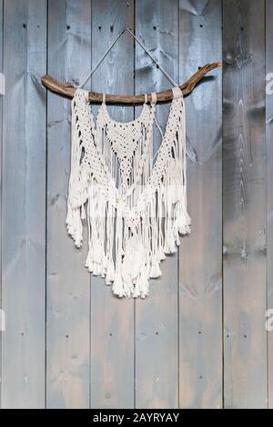 Handmade stylish cotton macrame decoration hanging on a white empty wall. Copy space. Stock Photo