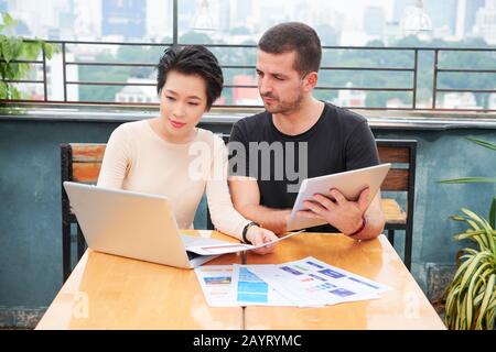 Product managers discussing interface design of new application or website when having meeting in cafe Stock Photo