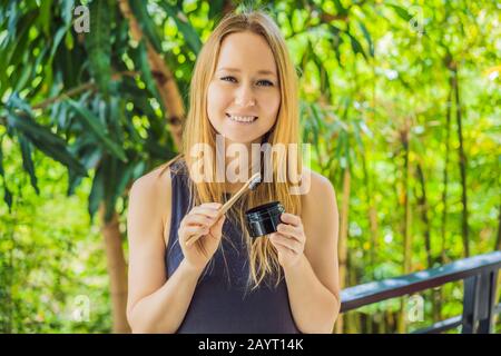 Young woman brush teeth using Activated charcoal powder for brushing and whitening teeth. Bamboo eco brush Stock Photo