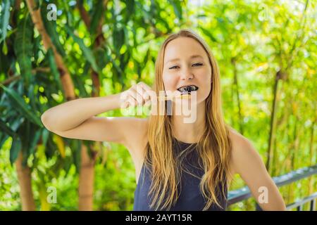Young woman brush teeth using Activated charcoal powder for brushing and whitening teeth. Bamboo eco brush Stock Photo