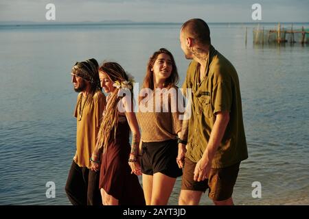 Happy couples holding hands when walking on beach and enjoying sunset sun Stock Photo