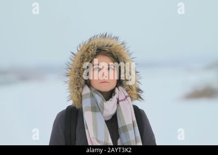A Girl in Fashionable Winter Clothes Stands Against the Background