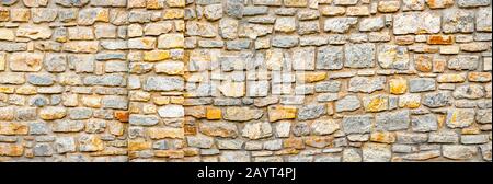 Stone wall banner, background. Wall pattern texture background. Surface with asymmetrical stones. Old wall of ancient architecture. Rome, greek culture, architecture. Fragment of historic building Stock Photo