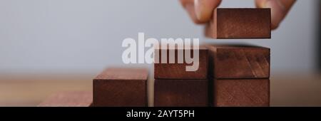 Male hand holds brown wood block of stair finish Stock Photo