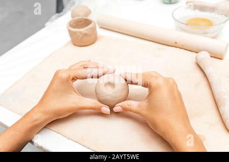 A close-up of a female potter hands holding a brown clay, workshop class Stock Photo