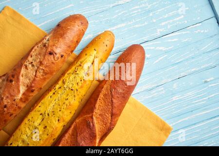 Three crispy french baguettes lie blue wooden background baguettes in assortment with sesame seeds Classic french national pastries Copy space Concept Stock Photo