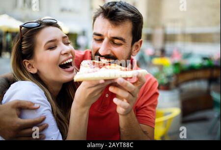 Happy couple eating pizza while traveling on vacation Stock Photo