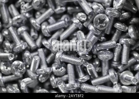 Pile of shiny new bolts, close-up background photo with selective soft focus Stock Photo