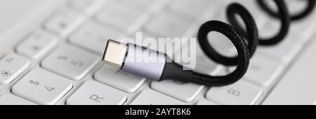 Usb type c cable against laptop keyboard background. Stock Photo