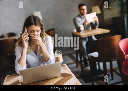 Portrait young shocked business woman sitting in front of laptop computer Stock Photo