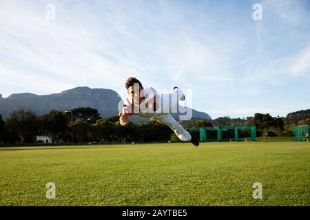 Cricket player trying to catch a cricket ball on the pitch Stock Photo