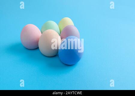 Easter Eggs painted in plain colors arranged in triangle shape on blue background with copy space Stock Photo