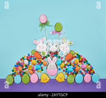 Light blue and violet background with sweets in shape of egg, bunny and chicken. Beautiful composition of delicious gingerbreads for Easter celebration. Stock Photo