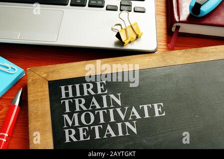 Staff hire, train, motivate and retain written on the blackboard. Stock Photo
