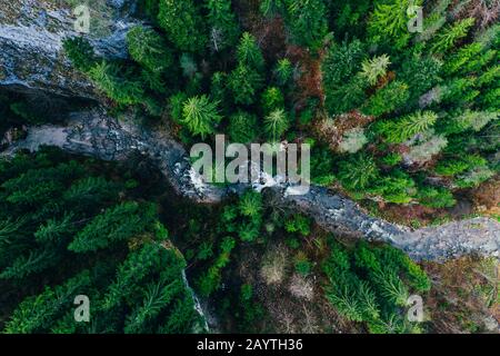 Creek winding through cliffs and forests seen from a drone Stock Photo