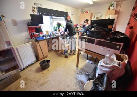 Lee Griffiths and Michelle Jones emptying out cupboards after flooding damaged their house on Rhyd-Yr-Helyg road in Nantgarw, south Wales, where residents are returning to their homes to survey and repair the damage in the aftermath of Storm Dennis. Stock Photo