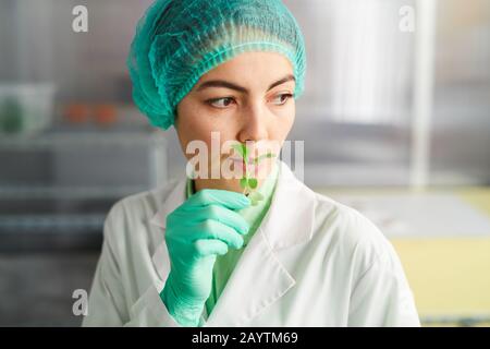 Portrait of female worker holding tiny green plant while working in bio laboratory, copy space Stock Photo