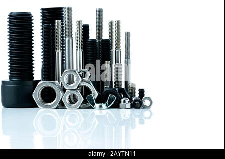 Metal bolts and nuts on white background. Fasteners equipment. Hardware tools. Stud bolt, hex nuts, and hex head bolts in workshop. Threaded fastener Stock Photo