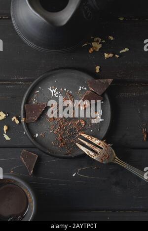 Black empty plate with cake leftovers from above on wooden background Stock Photo