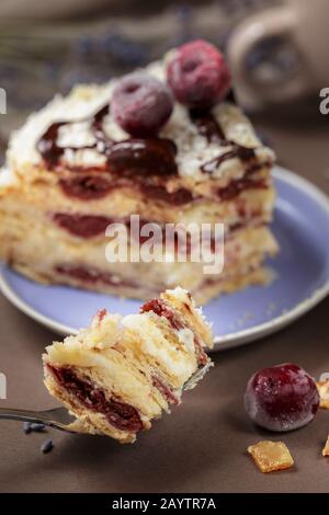 A piece of delicious summer cherry cake on a lavender color plate with cup of tea, closeup Stock Photo