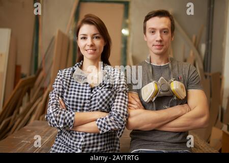 Male and woman joiners with arms crossed in workshop Stock Photo