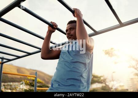 Muscular young athletic fit african american man working out at an outdoor gym doing pull ups Stock Photo