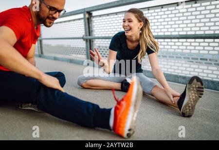 Happy young couple people stretching before running outdoors Stock Photo