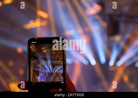 Scene, stage lights with colored spotlights and smoke, laser lights background displayed in the screen of a smartphone Stock Photo