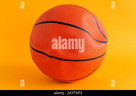 Deflated basketball ball on yellow background, close up selective focus Stock Photo