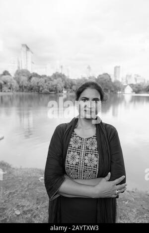 Mature beautiful Indian woman with arms crossed at the park Stock Photo