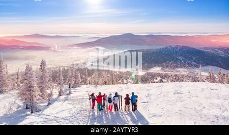Happy snowboarders and skier having fun and posing with snowboards and ski on top mount sunrise. Aerial top view Stock Photo