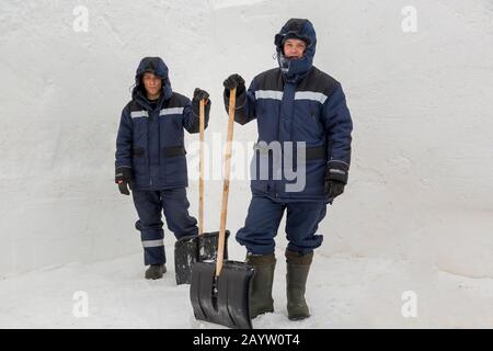 Two workers in blue jackets for snow removal Stock Photo