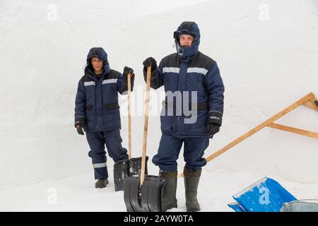 Two workers in blue jackets for snow removal Stock Photo