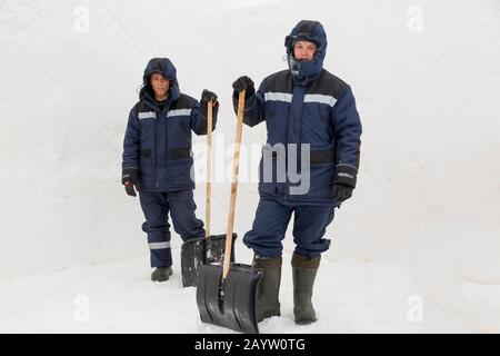 Two workers in blue jackets for snow removal Stock Photo