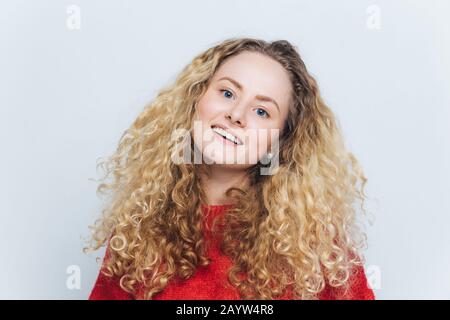 Glad lovely adorable young beautiful woman wth curly hair, dressed casually, expresses positive emotions and feelings being satisfied to have date wit Stock Photo