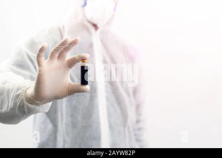 Scientist with a mask holding bottle of vaccine developed for corona virus. Covid-19 antidote. Doctor discovers treatment for epidemic disease. Global Stock Photo