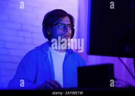 Concentrated Hacker Working On PC Computer Sitting Indoor, Low Light Stock Photo
