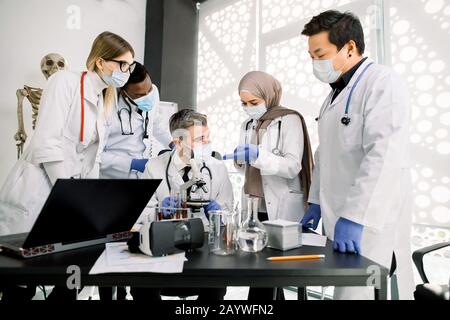 science, chemistry, technology, biology and medicine concept. Team of multiethnic young scientists discussing while conducting scientific research Stock Photo