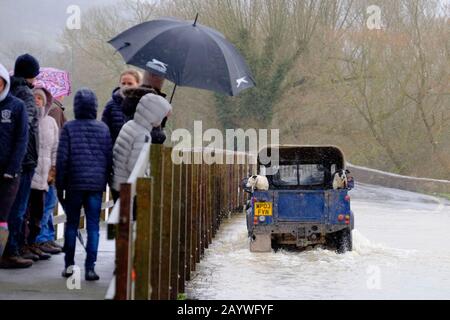 Lacock, Wiltshire, UK. 17th Feb, 2020. The River Avon in Lacock has burst its banks and flooded the road out of the village. The road is passable with caution. Local people look on and the dogs enjoy the ride. Credit: Mr Standfast/Alamy Live News Stock Photo