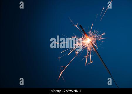 Burning sparkler bengal fire on blue background Stock Photo