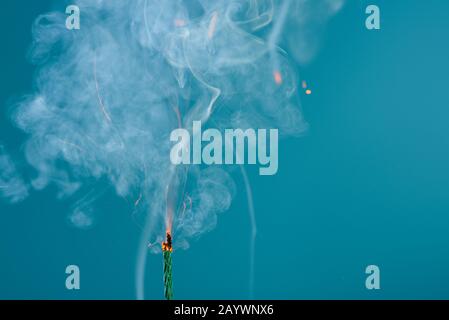 Burning green fuse wick cord with sparks and smoke on blue background Stock Photo