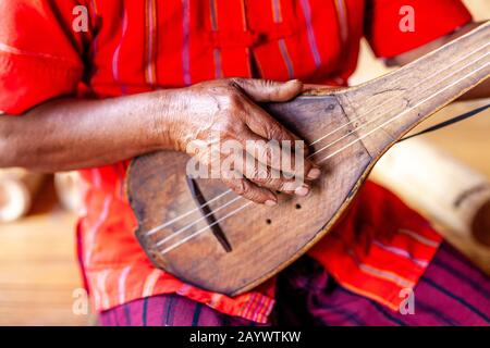 A Man From The Kayah Ethnic Group Playing A Guitar Like Instrument, Hta Nee La Leh Village, Loikaw, Kayah State, Myanmar. Stock Photo