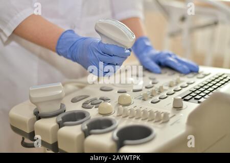 Ultrasound scanner sensor with gel in hand, view from the patient side, at the doctor through the control panel. Stock Photo
