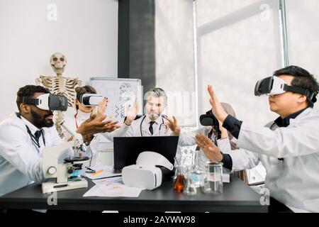 Biotechnology, chemistry, science, healthcare, vr concept. Medical diagnostic specialists, scientists, doctors wearing vr goggles analyzing new Stock Photo