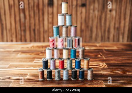 Many overlaped thread spools in a pyramid shape on a wooden background Stock Photo